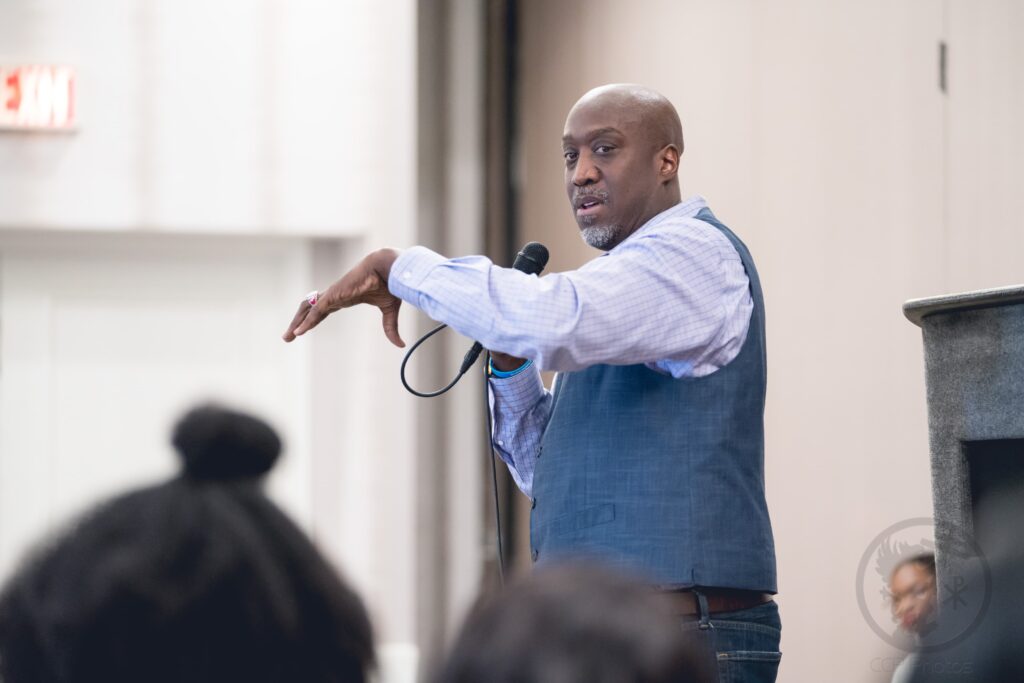 Mark Wiggins speaking on stage holding a microphone.